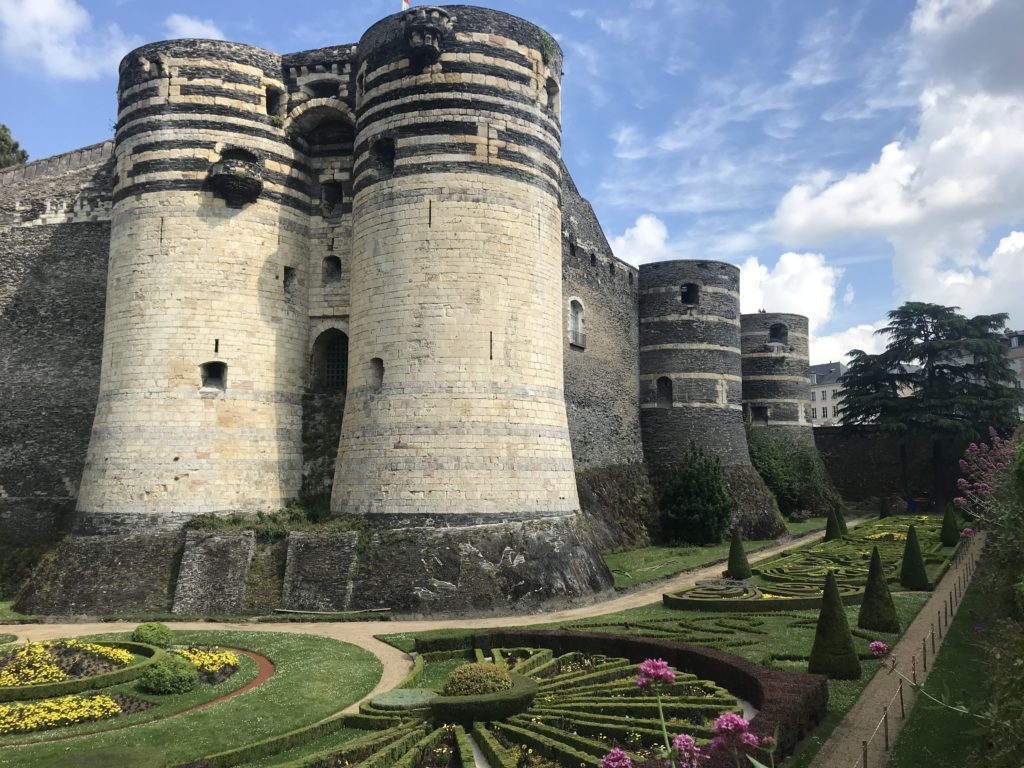 4 towers of the medieval Angers Castle can be seen, 2 flanking a door, as well as part of the garden at their base.